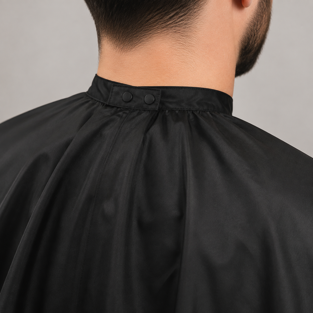 Close view of the American Crew black cutting cape snap closure and shoulder coverage