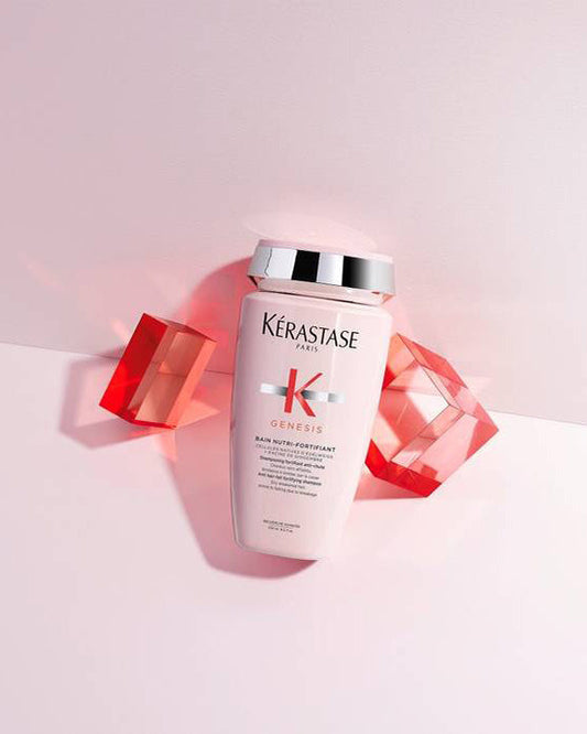 Kérastase Genesis Bain Nutri-Fortifiant shampoo bottle lying among pink and red acrylic blocks