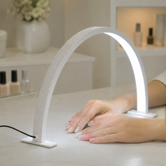 White LED half-moon nail lamp illuminating hands on a salon workstation