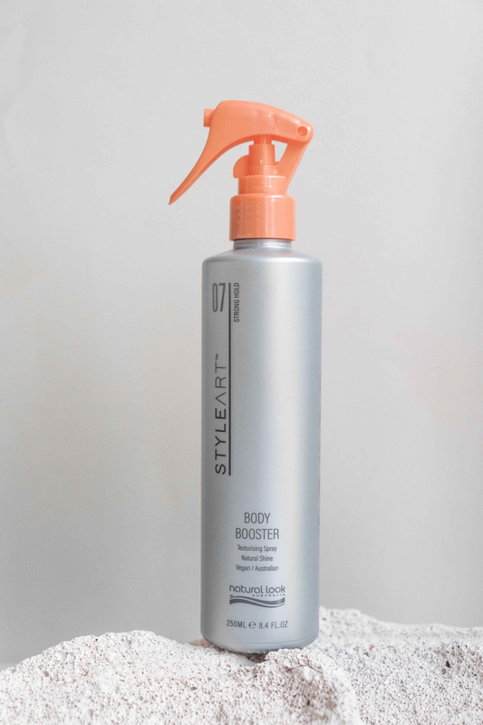 Natural Look StyleArt Body Booster 250ml silver bottle with orange trigger sprayer on a stone surface