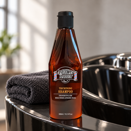American Barber Thickening Shampoo 300ml bottle beside a black salon wash basin and charcoal towel