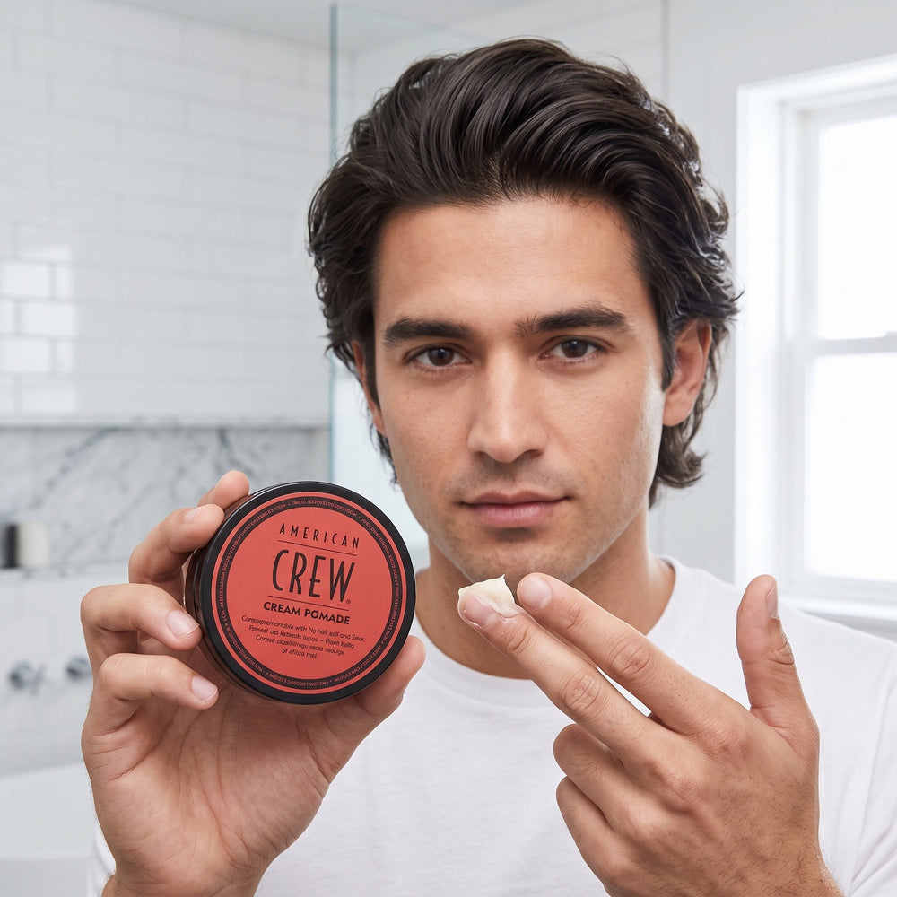 Man holding a tin of American Crew Cream Pomade and styling his hair