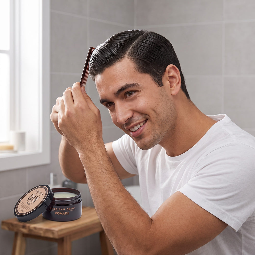 Man combing his hair with American Crew Pomade in front of a mirror