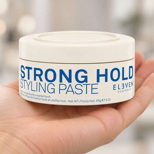 Eleven Australia Strong Hold Styling Paste 85g held in a salon, with the product label visible.