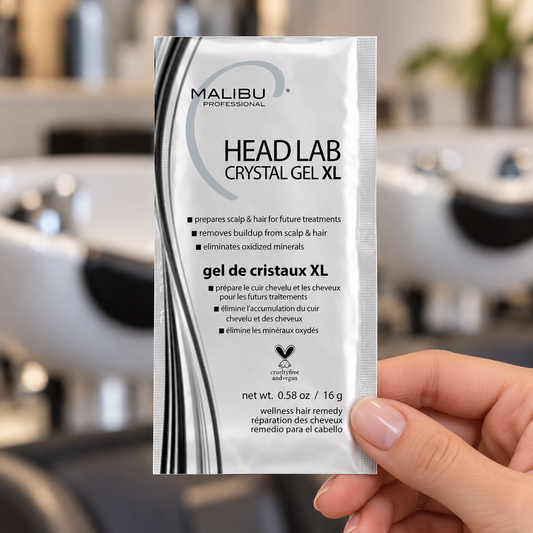 Malibu C Head Lab Crystal Gel XL 16g sachet held beside a salon shampoo station.