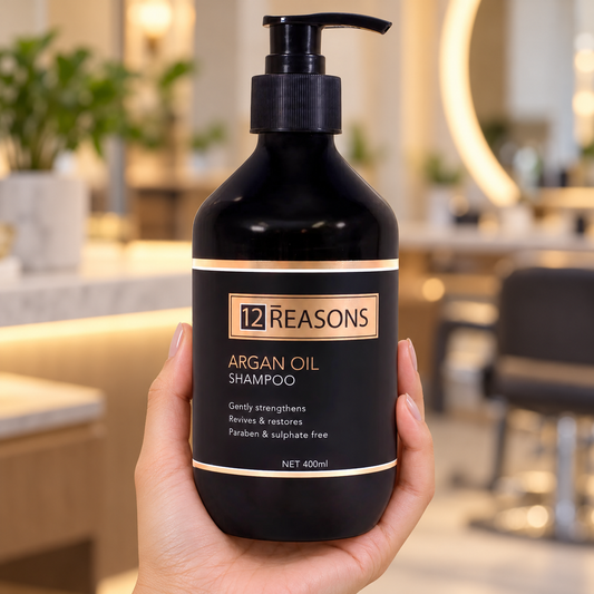 12 Reasons Argan Oil Shampoo 400ml pump bottle supported in a hand with its label visible.