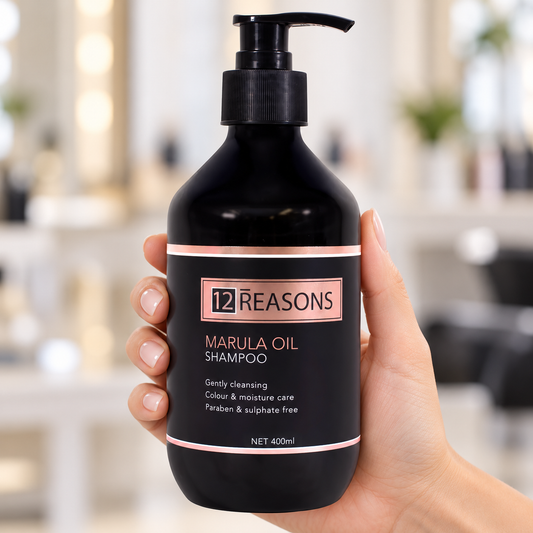 12 Reasons Marula Oil Shampoo 400ml pump bottle held upright in a salon.