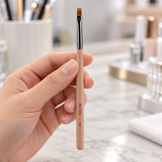 ACOS number 12 nail art brush held by a nail technician, showing the bristles, metal ferrule and peach handle