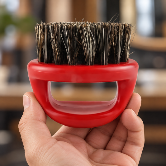 Red loop-handle beard brush held in a hand, showing the open grip and dark bristles.