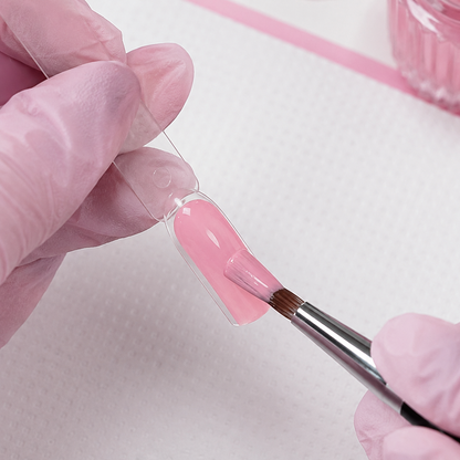 Professional application of Baby Pink 004 gel colour to an artificial nail swatch