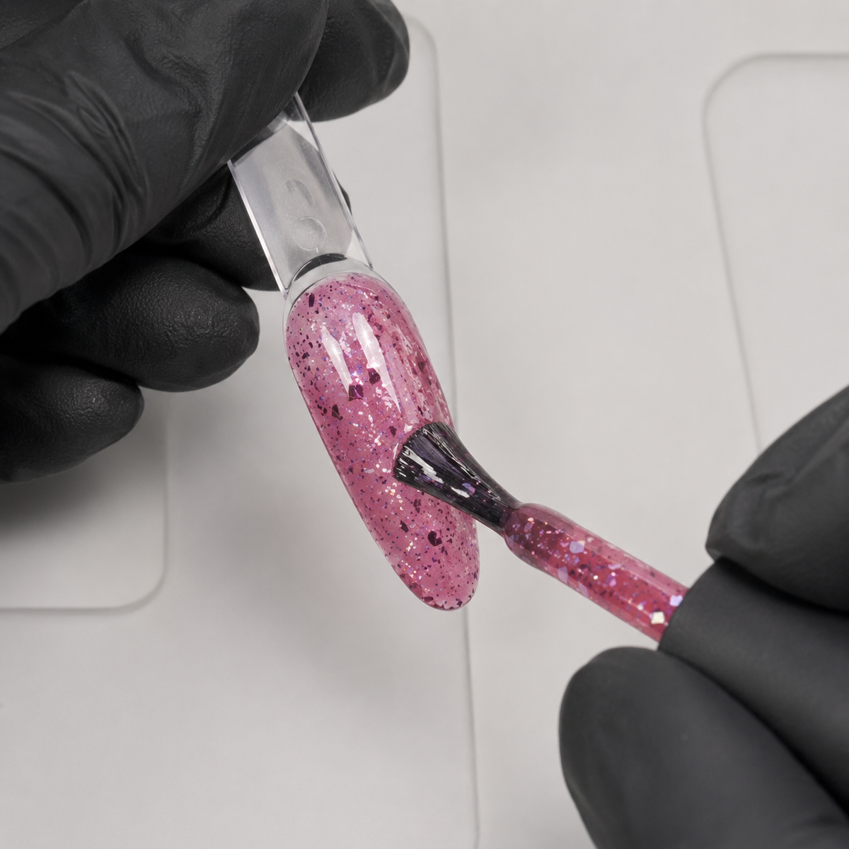 Gloved nail technician applying ACOS HF094 Glitter Dark Pink gel to an artificial practice tip.