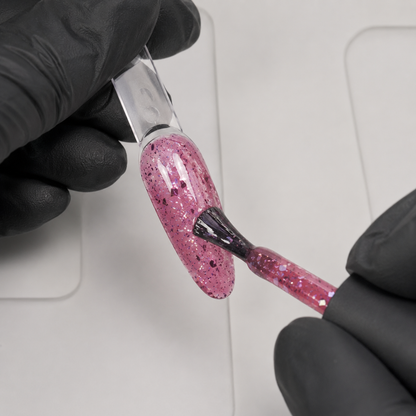Gloved nail technician applying ACOS HF094 Glitter Dark Pink gel to an artificial practice tip.