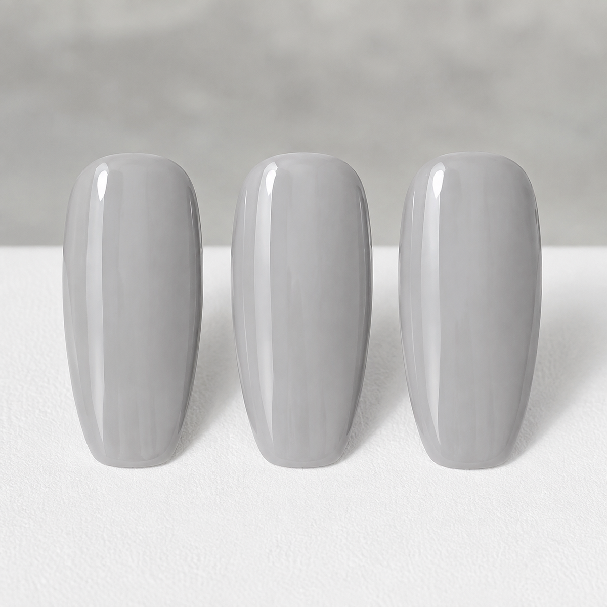 Cured ACOS Light Grey 037 gel colour on three artificial nail swatches
