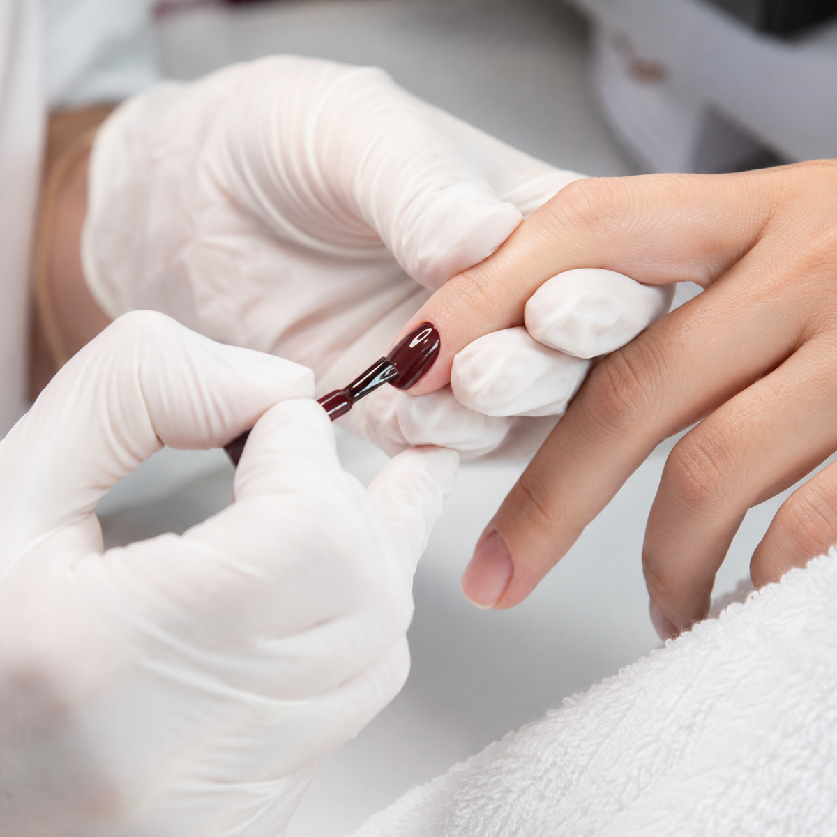 Professional applying deep brown-red 052 gel colour to a fingernail