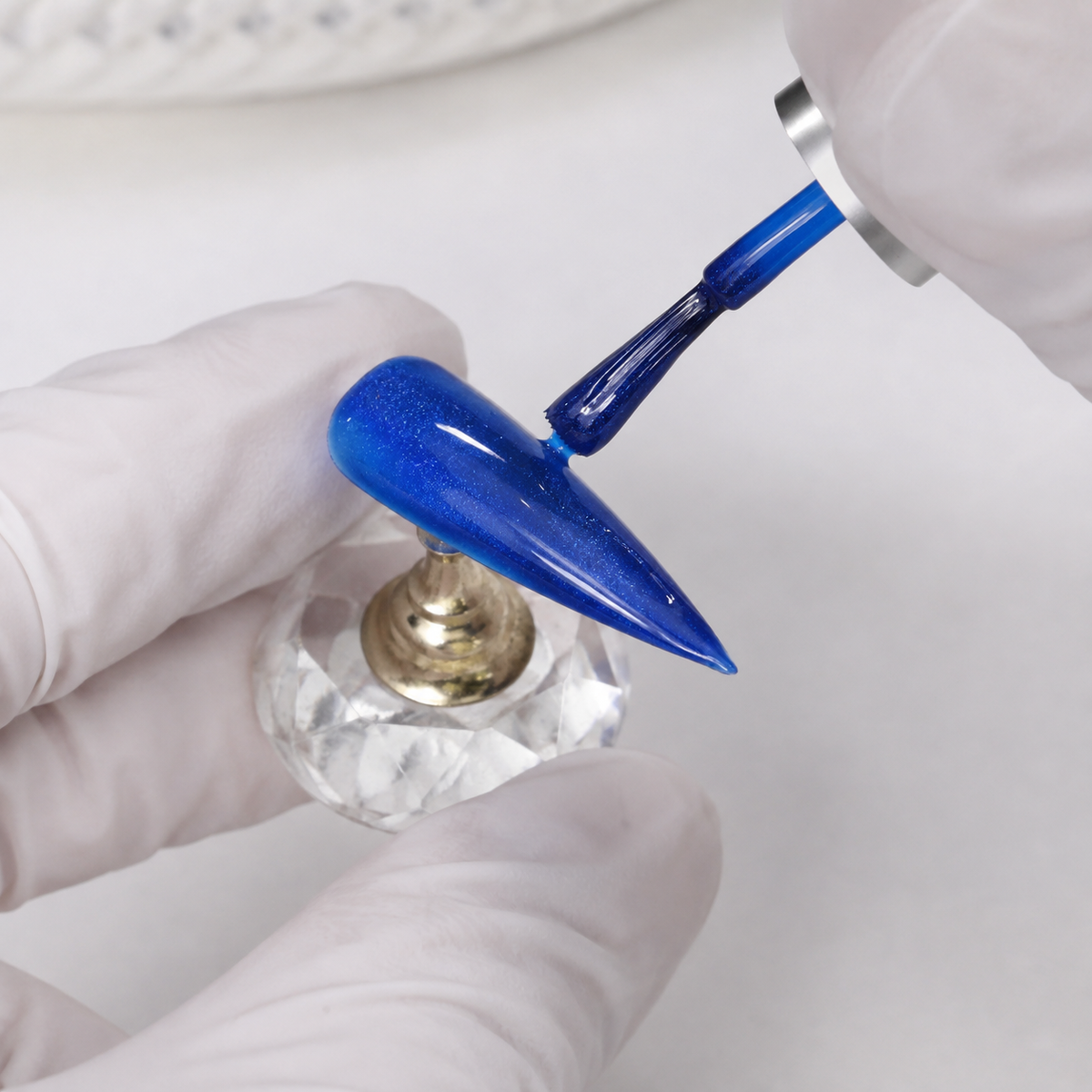 Professional applying ACOS Glossy Blue 100 gel to an artificial nail tip