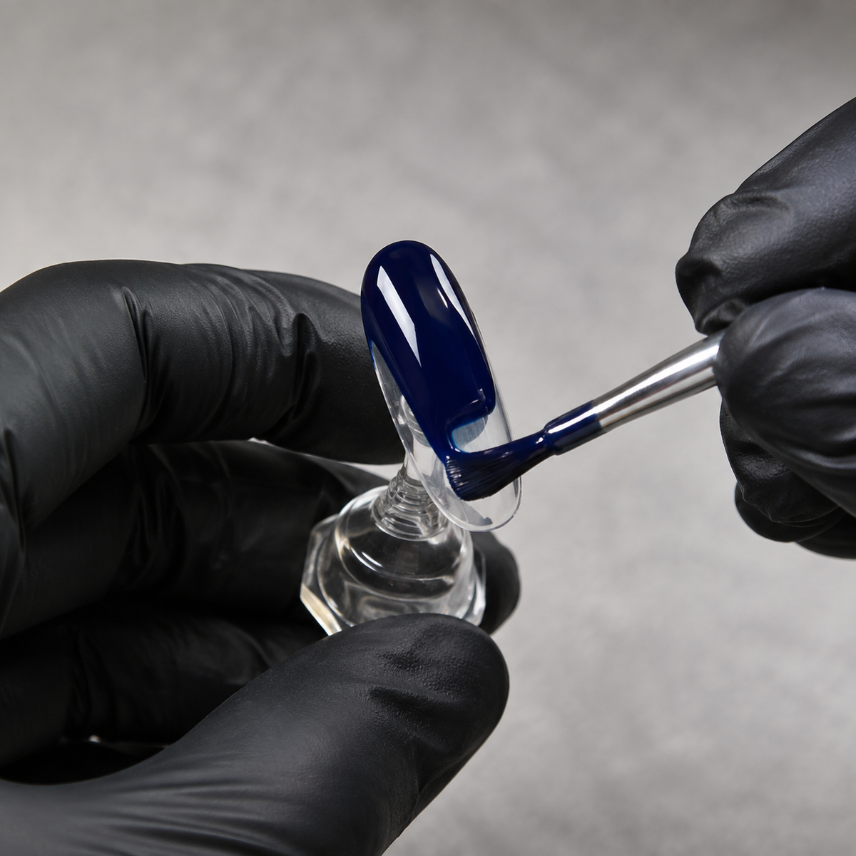 Professional application of Glossy Dark Blue 095 gel polish to a nail display tip.