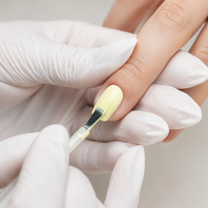 Professional applying pale Snow Yellow 021 gel polish to a fingernail