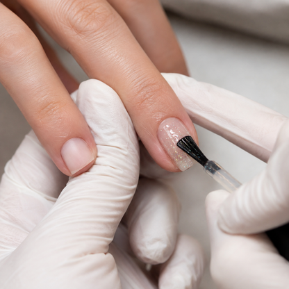 Professional applying ACOS 083 transparent glitter mix to a prepared fingernail