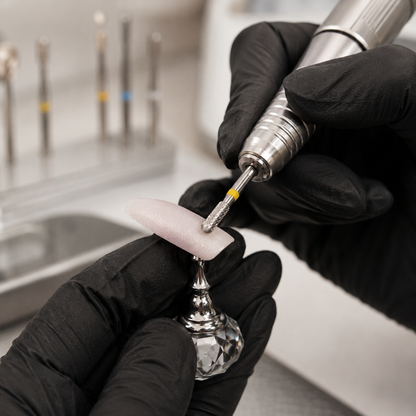 ACOS pear nail drill bit used by a gloved technician on an artificial practice nail tip