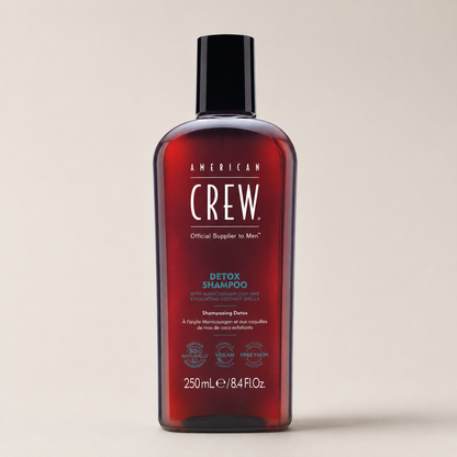American Crew Detox Shampoo 250ml bottle at a three-quarter angle on a warm-grey studio background