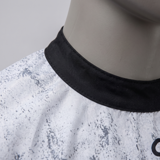 Close detail of The Dapper Barber cape's black collar and distressed monochrome fabric