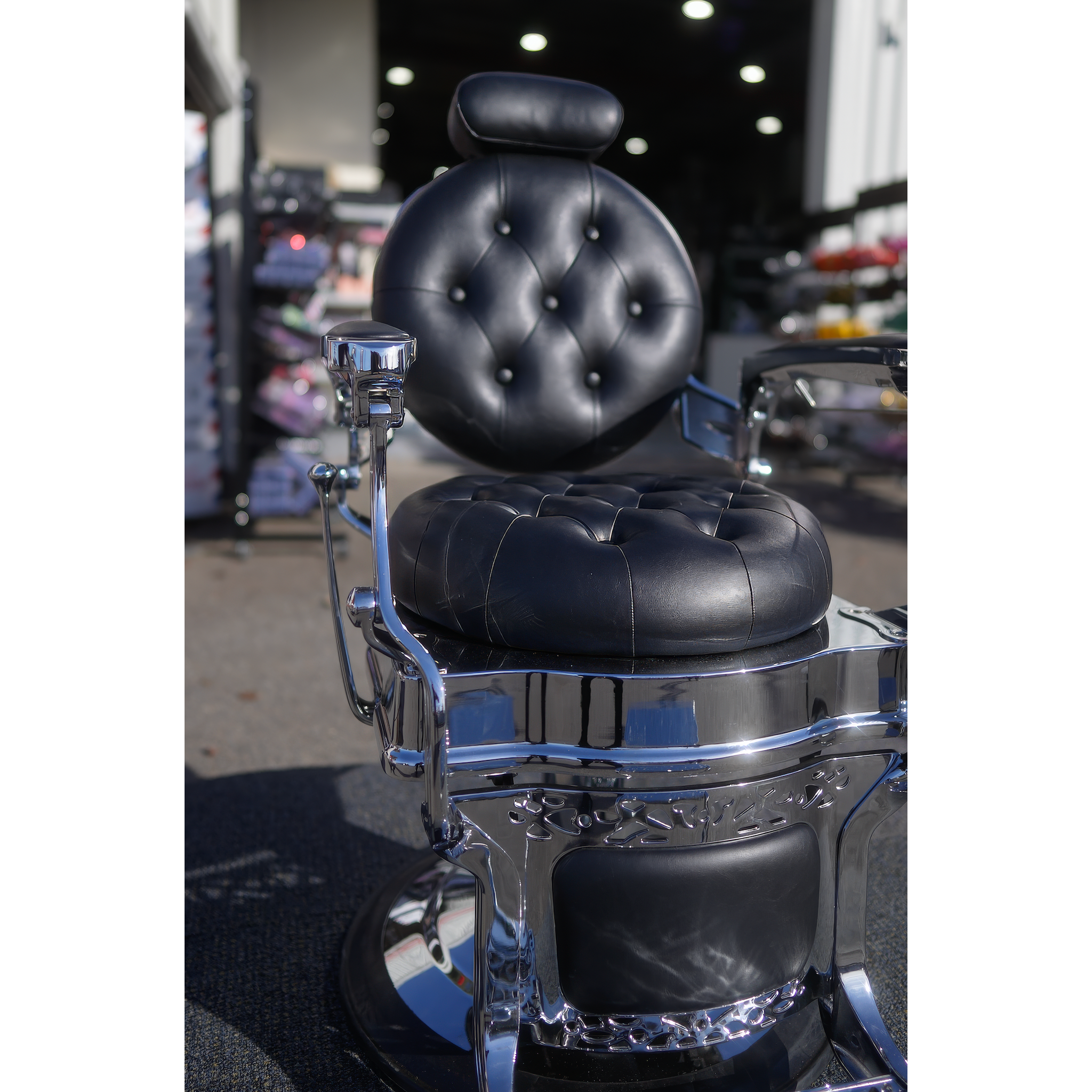 Black tufted barber chair with ornate chrome frame and hydraulic base