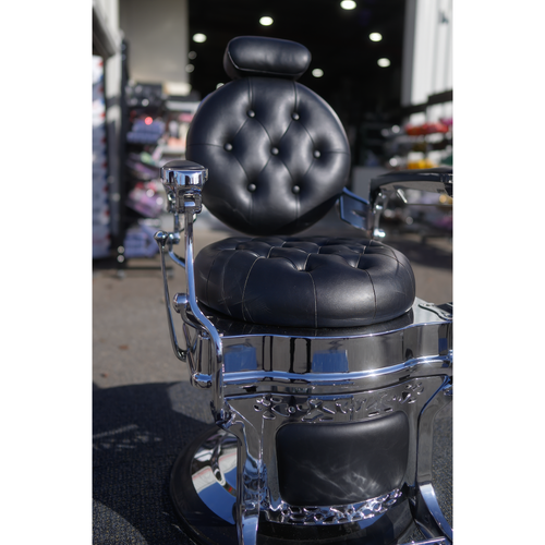Black tufted barber chair with ornate chrome frame and hydraulic base