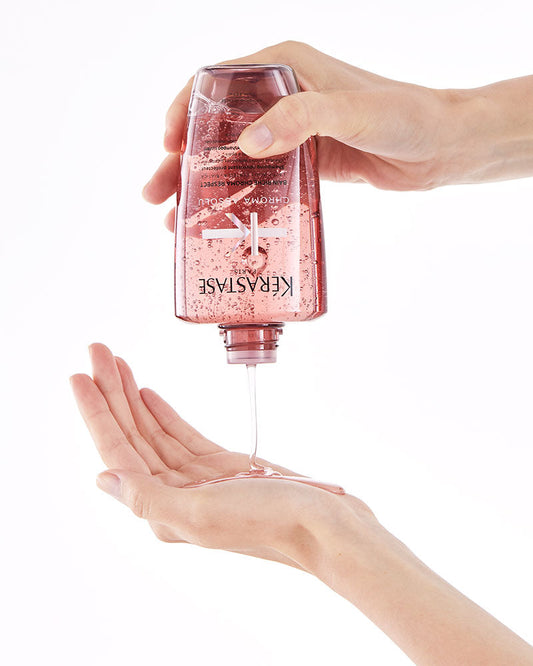 Hand pouring Kérastase Bain Riche Chroma Respect shampoo into an open palm
