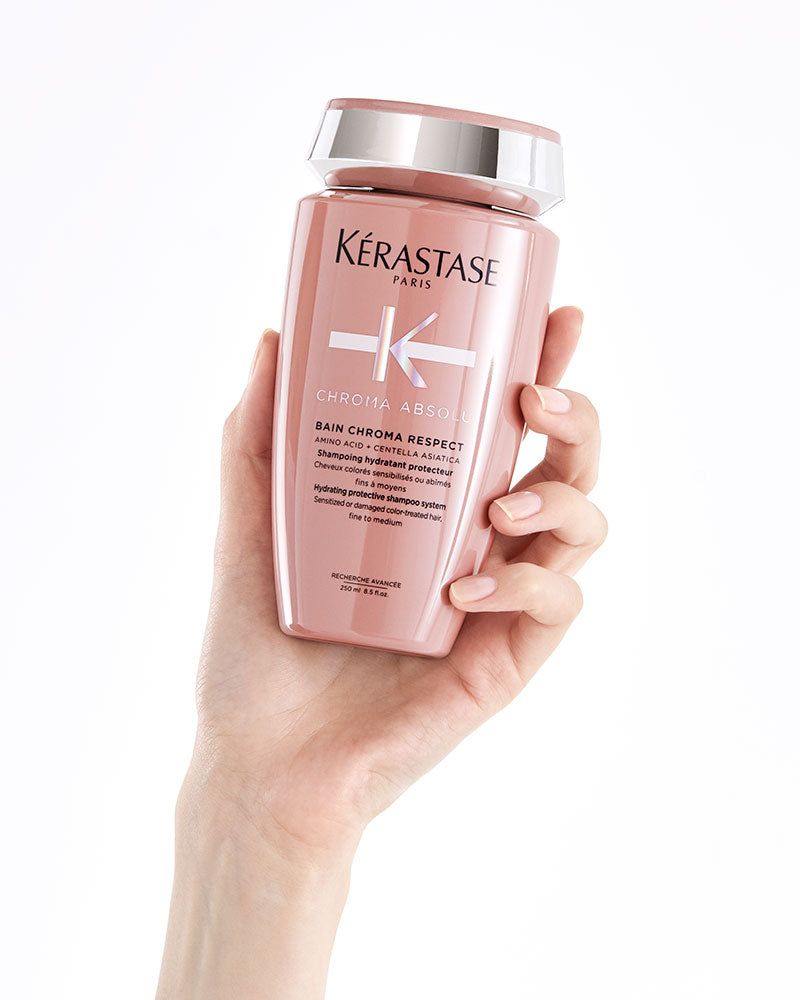 Hand holding a bottle of Kérastase Chroma Absolu Bain Chroma Respect shampoo
