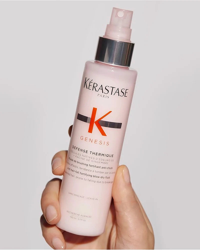 Hand holding a bottle of Kérastase Genesis Défense Thermique heat protectant