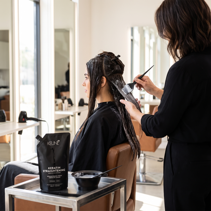 Stylist applying Keune Keratin Straightening Cream in salon
