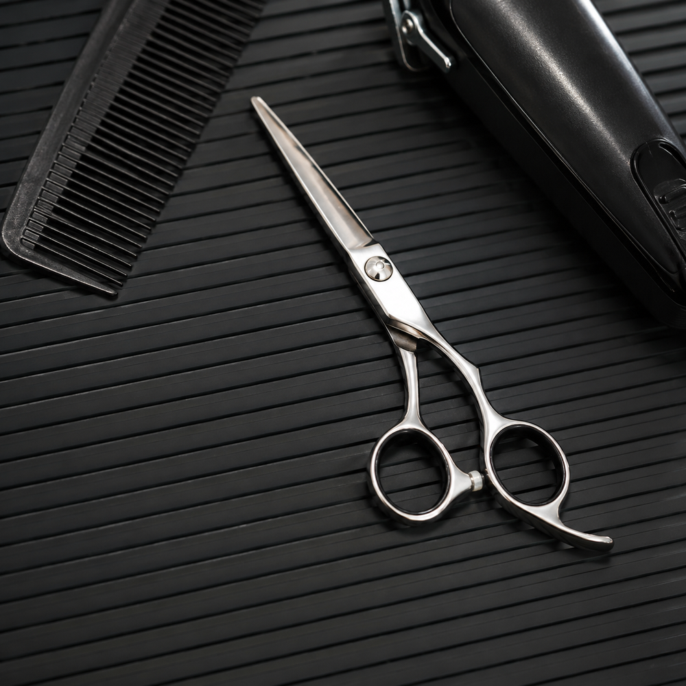 Close detail of comb, scissors and trimmer arranged on a black ribbed barber mat
