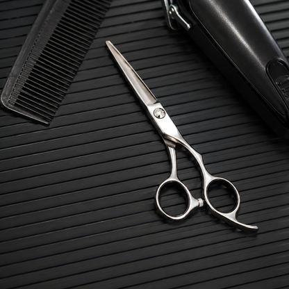Close detail of comb, scissors and trimmer arranged on a black ribbed barber mat