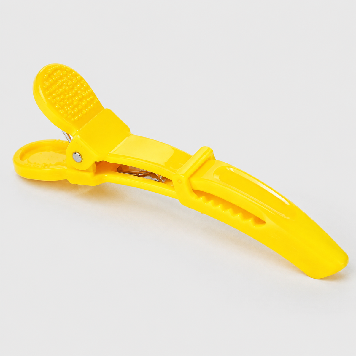 Yellow crocodile hair clip close-up showing spring hinge and serrated gripping jaws