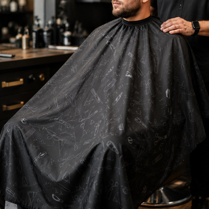Printed barber cape draped across an adult client’s shoulders and torso