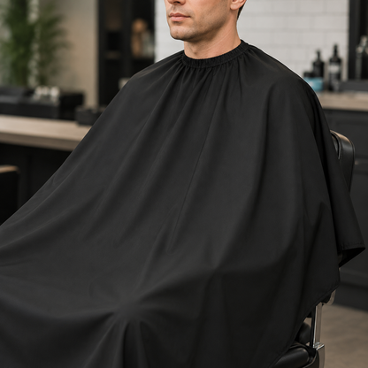 Close view of a client wearing a plain black barber cape with full shoulder-to-lap coverage