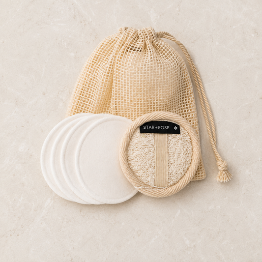 Reusable makeup remover pads, hemp scrubbie and cotton wash bag arranged on stone