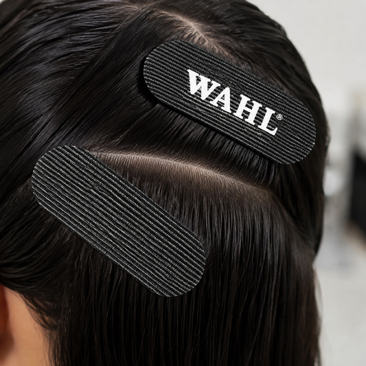 Two black WAHL sectioning grips holding sections of dark hair