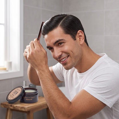 Man combing his hair with American Crew Pomade in front of a mirror