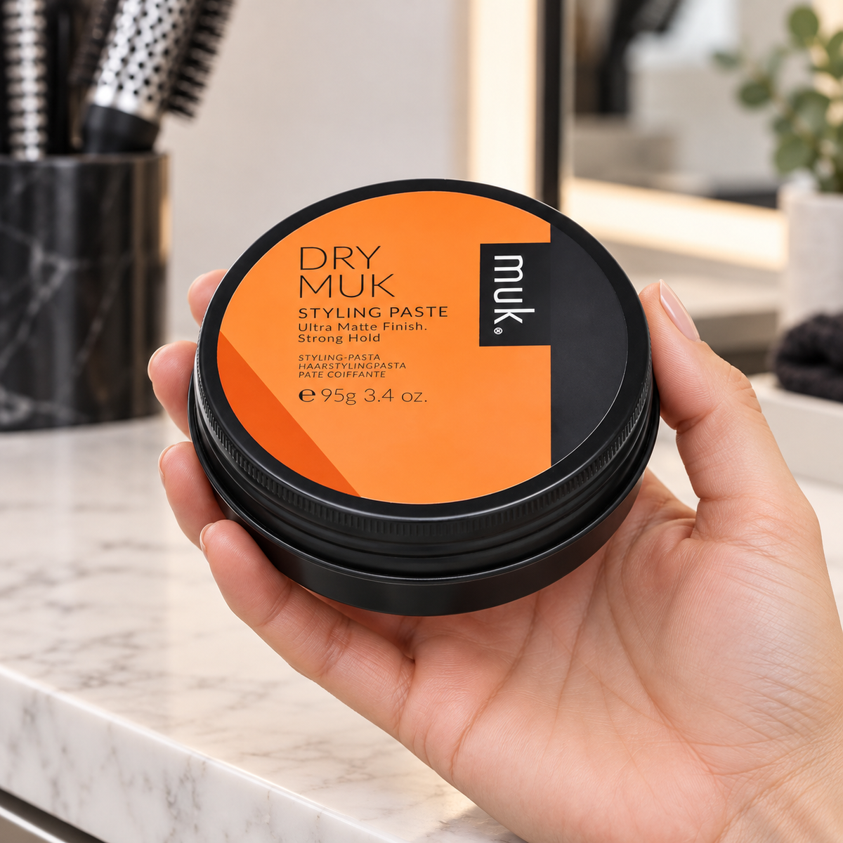 Dry muk Styling Paste 95g shown being handled at a salon station.