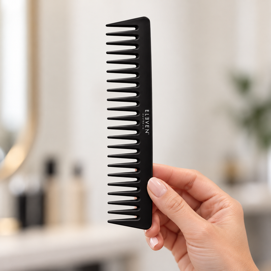 ELEVEN Australia Black Wide Tooth Comb held in a salon, with the product label visible.