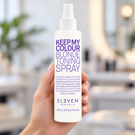 Eleven Australia Keep My Colour Blonde Toning Spray 200 ml held in a salon with its label and spray nozzle visible.