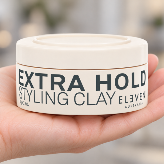 Eleven Australia Extra Hold Styling Clay 85g held in a salon, with the product label visible.
