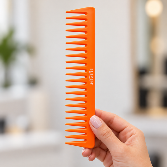 Eleven Australia Neon Orange Comb held in a salon, with the product label visible.