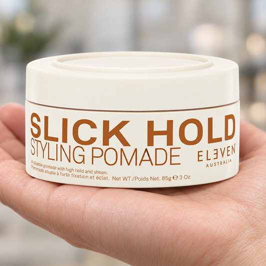 Eleven Australia Slick Hold Styling Pomade 85g held in a salon, with the product label visible.