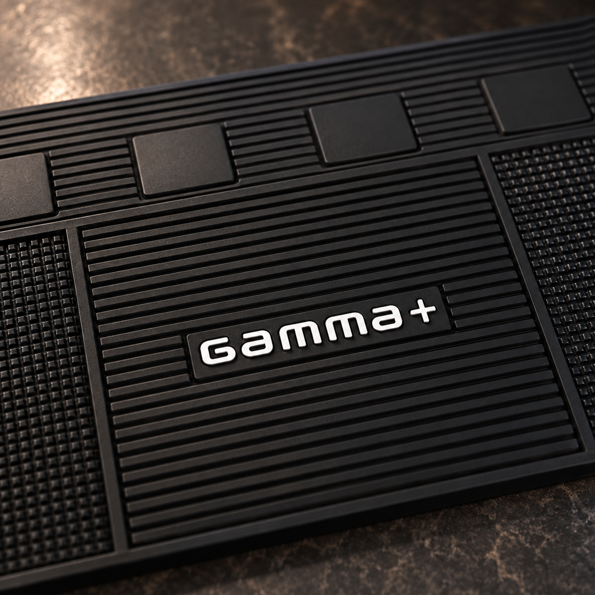 Close-up of the Gamma+ barber mat central grooves, logo and textured rubber.