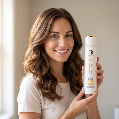 Smiling woman holding GK Hair Moisturizing Shampoo