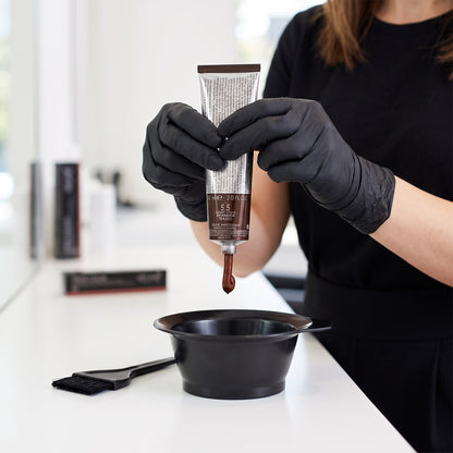 Colourist in black gloves squeezing Keune Tinta Color 5.5 into a mixing bowl