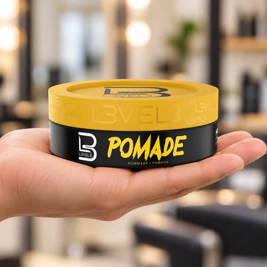 L3VEL3 Hair Styling Pomade 150ml with yellow lid held at a barber station.