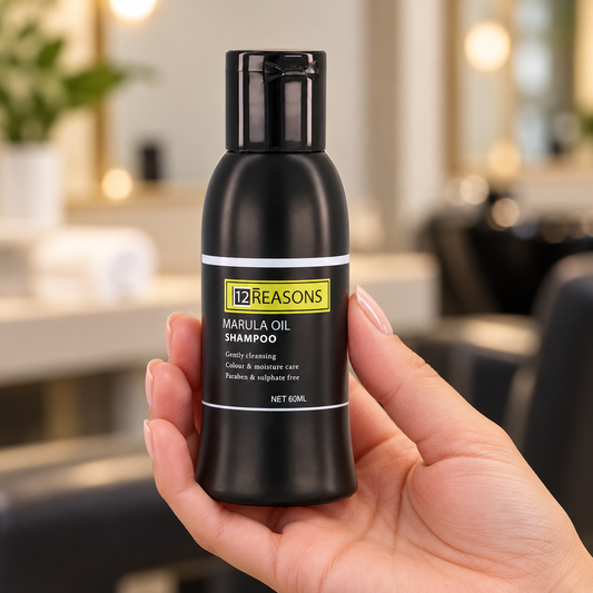 12 Reasons Marula Oil Shampoo 60ml travel bottle held with its cap closed and label visible.